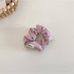 Satin bow scrunchie displayed next to matching satin fabric swatches