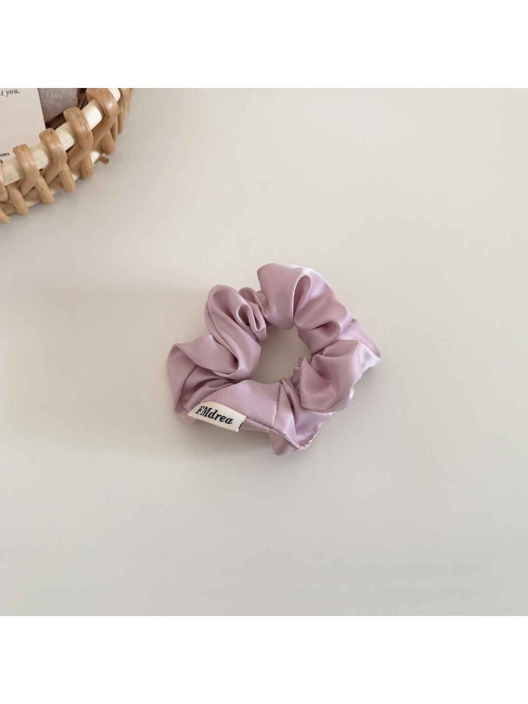 Satin bow scrunchie displayed next to matching satin fabric swatches
