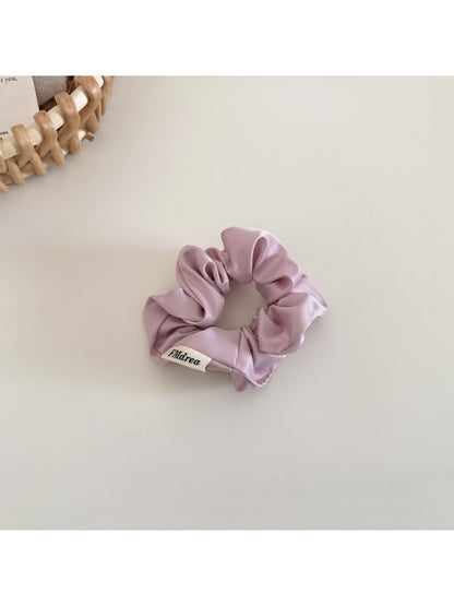 Satin bow scrunchie displayed next to matching satin fabric swatches