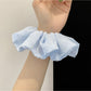 Gifty scrunchie displayed on a wooden surface highlighting its striped pattern