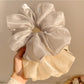 Close-up of Gifty minimalist chic shiny scrunchie in soft pink fabric