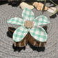 Beau checkered flower hair clip displayed on a wooden surface with natural lighting