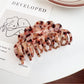 Beau claw clip in light tortoiseshell with wavy edges on a wooden table