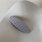 Beau polka dot hair clip displayed on a pastel colored background