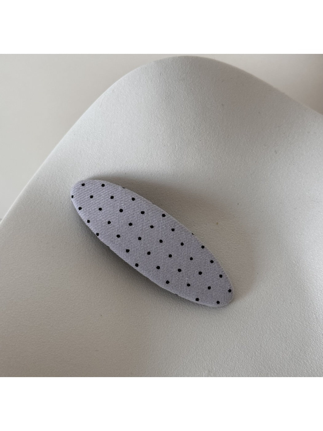 Beau polka dot hair clip displayed on a pastel colored background