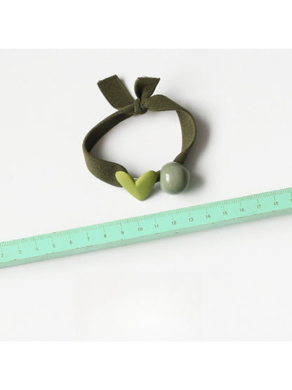 Yellow hair tie with a red heart charm shown in hand