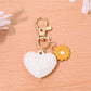Heart shaped bag charm keychain hanging from a backpack zipper pull