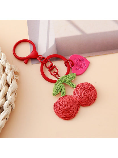 Keypus cherry charm keychain displayed on a wooden surface with soft lighting