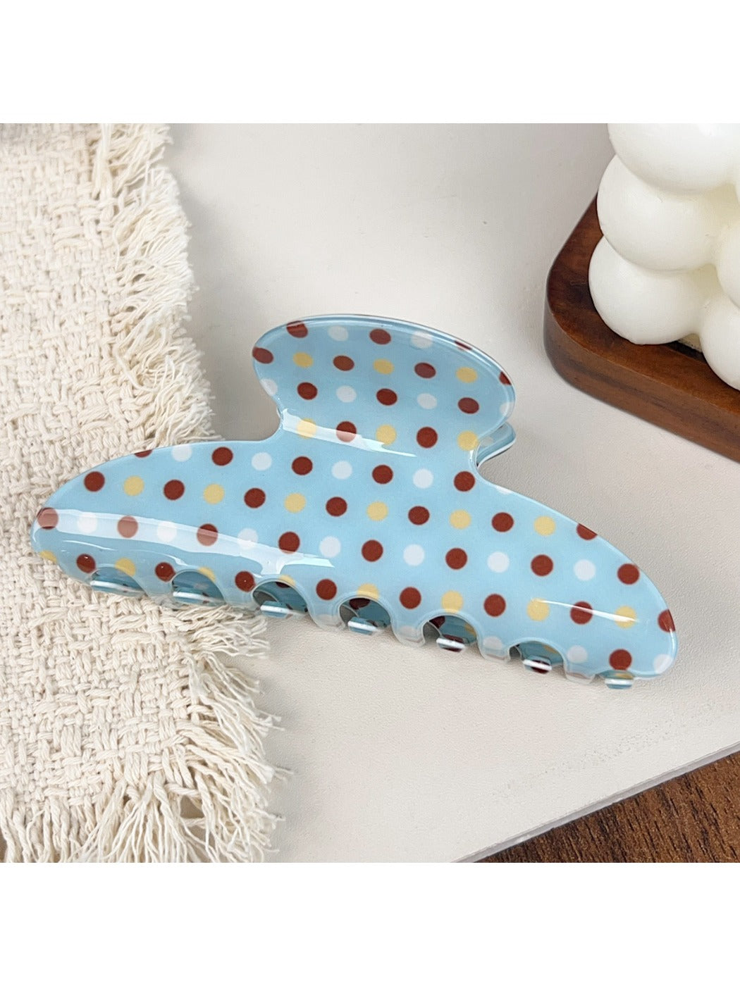 Blue hair claw clip with white polka dots resting on a wooden surface