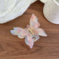 Butterfly shaped claw clip in pastel pink clipped onto hair