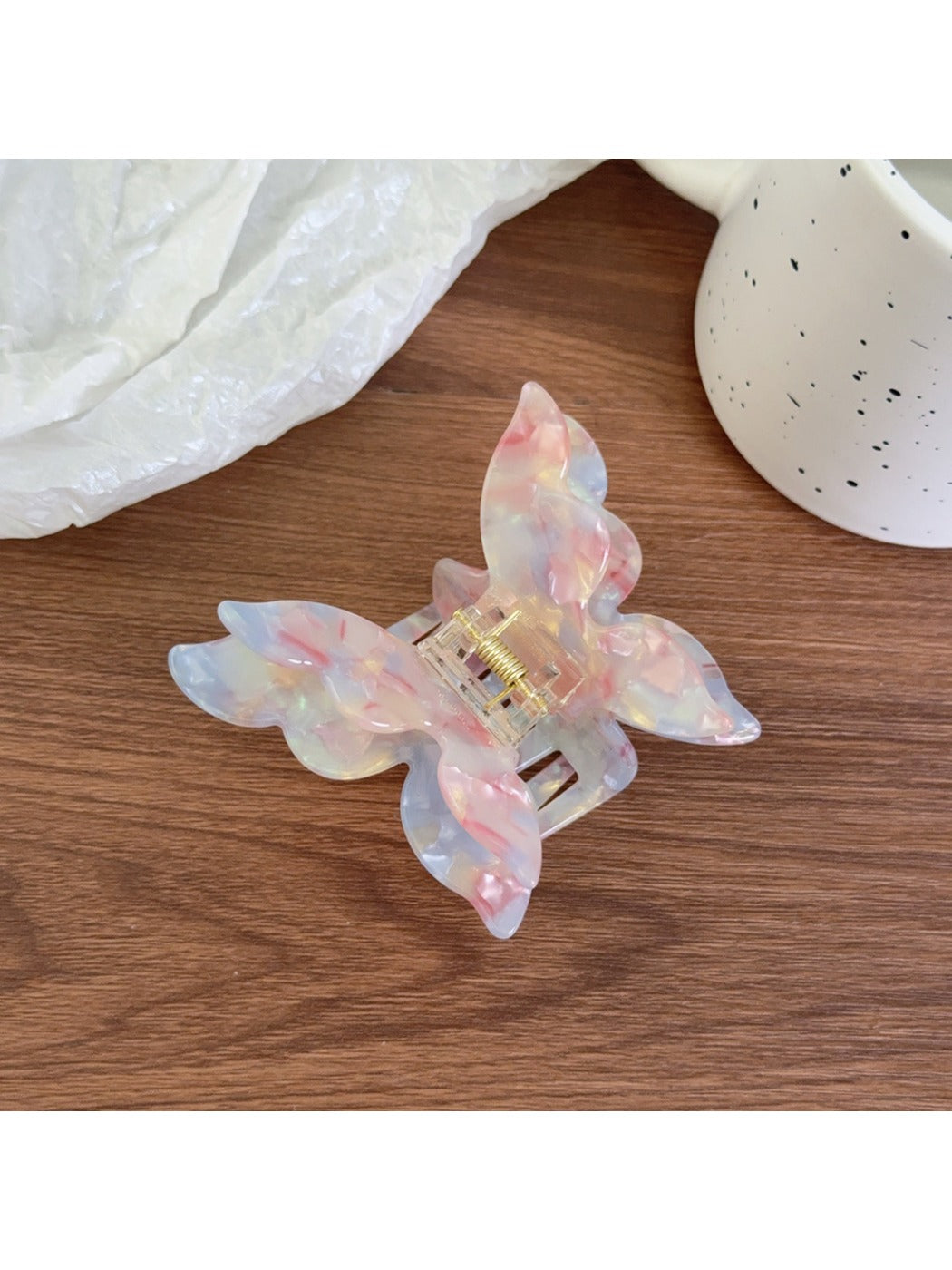 Butterfly shaped claw clip in pastel pink clipped onto hair