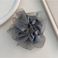 Ruffled scrunchie wrapped around a ponytail on a model with dark hair