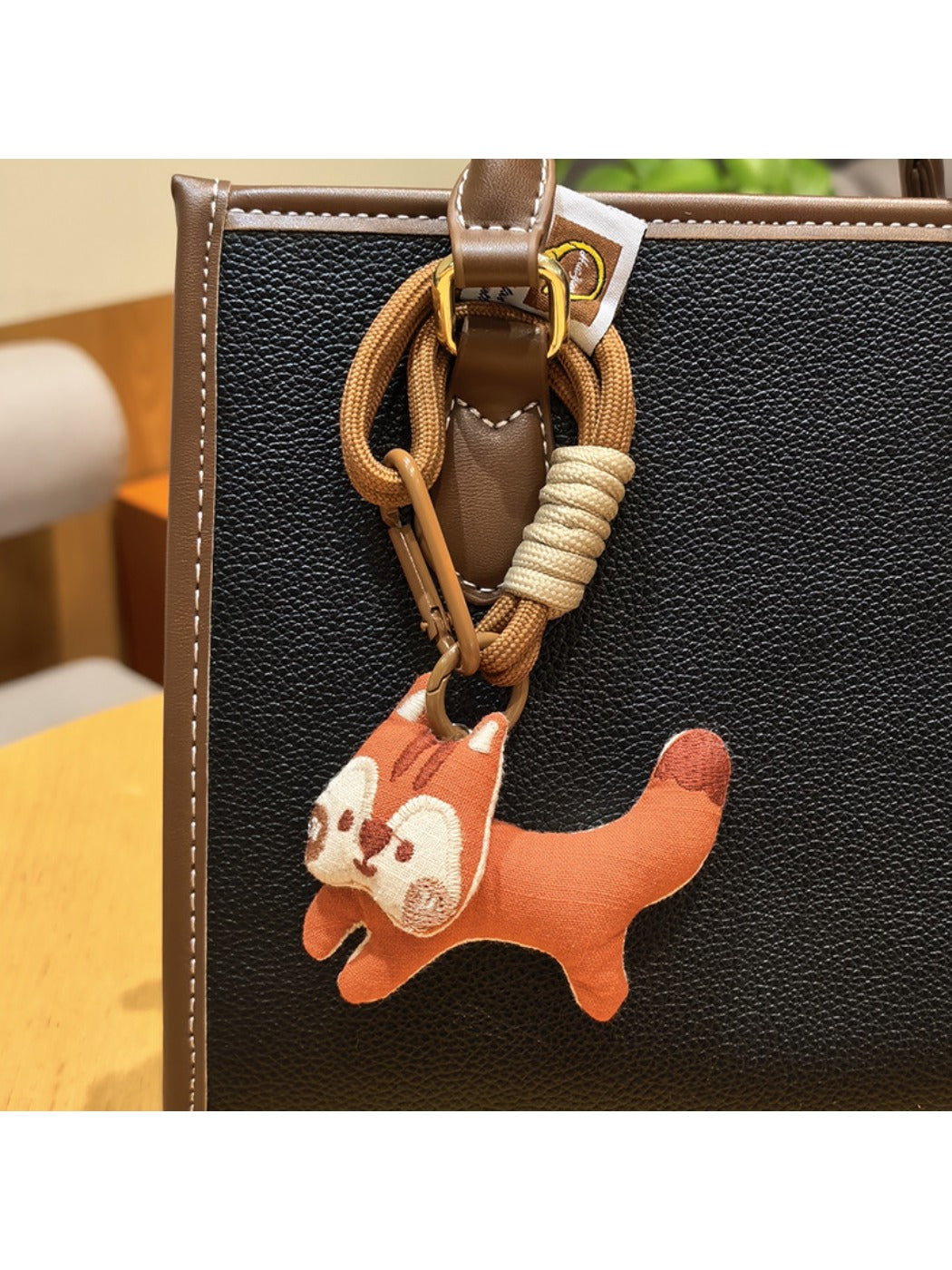 Keypus squirrel charm keychain attached to a set of keys on a wooden surface