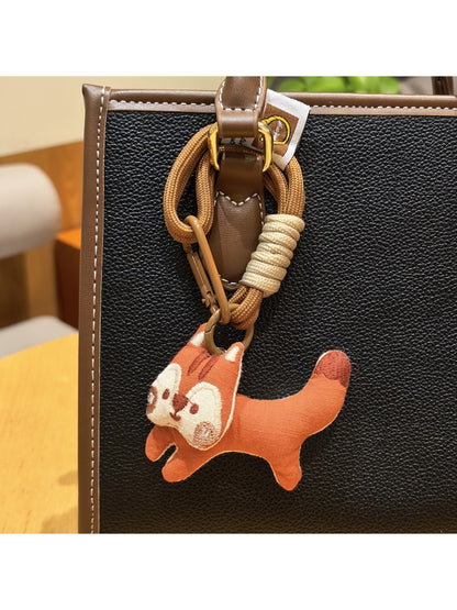 Keypus squirrel charm keychain attached to a set of keys on a wooden surface