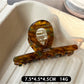 Beau acetate claw clip resting on a wooden surface with natural lighting