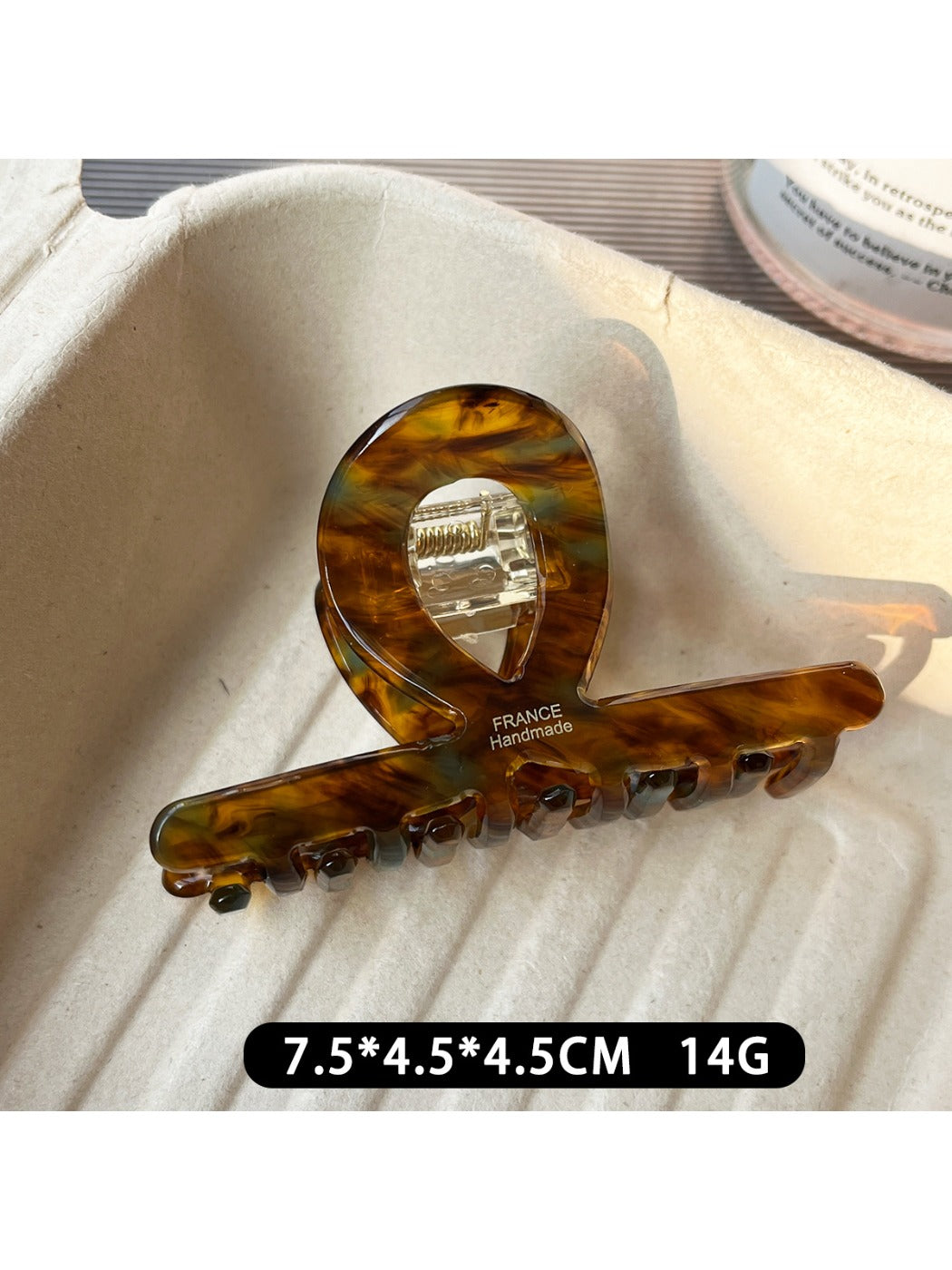 Beau acetate claw clip resting on a wooden surface with natural lighting
