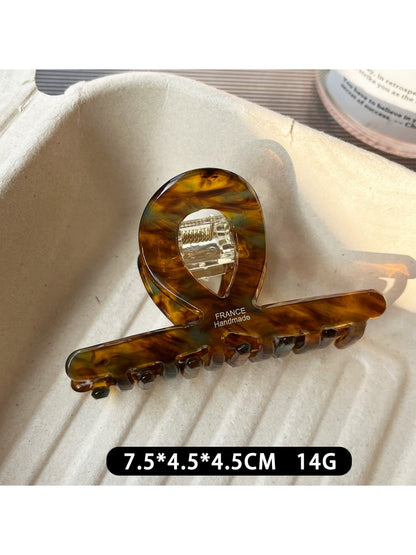 Beau acetate claw clip resting on a wooden surface with natural lighting