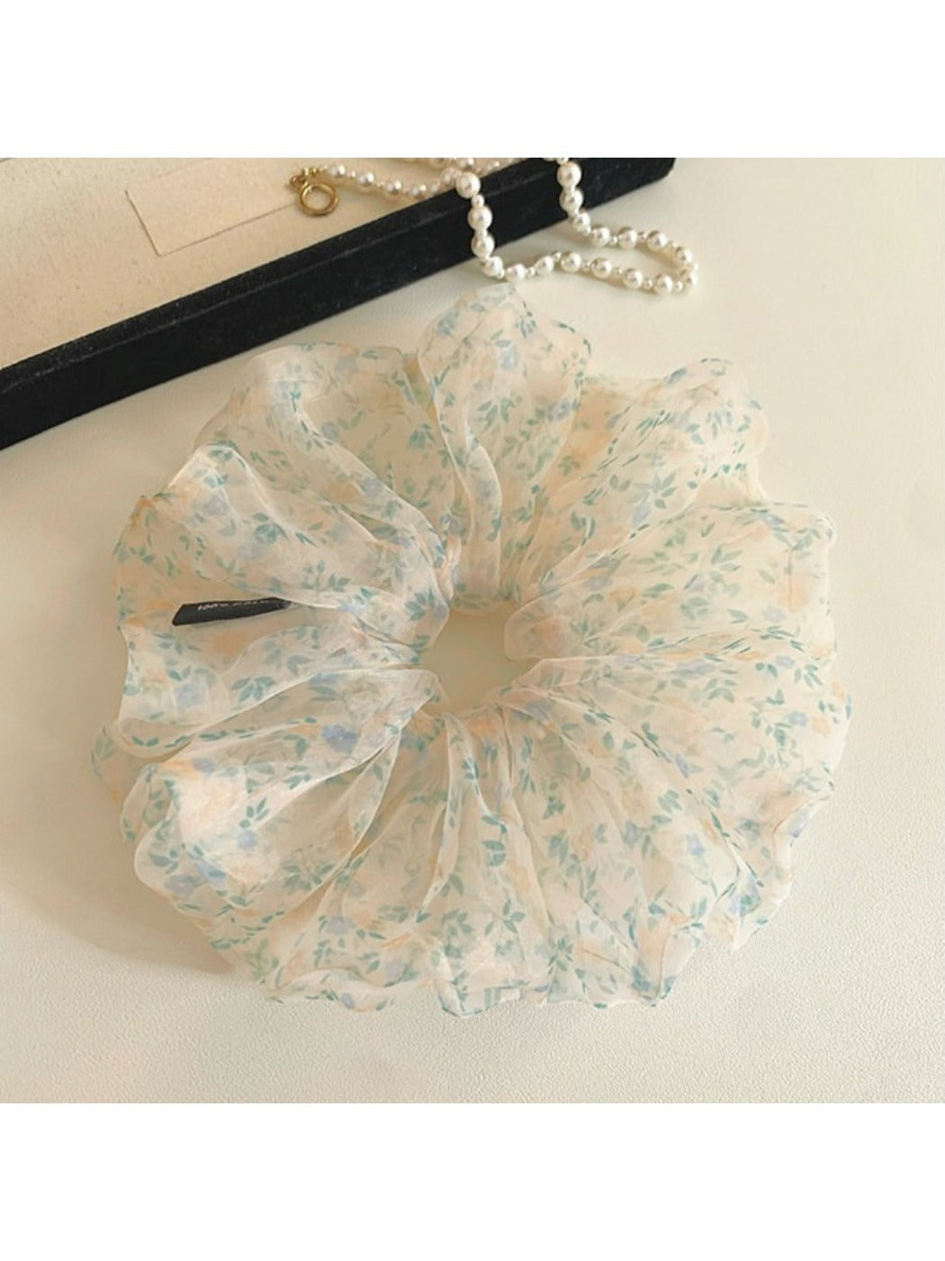 Close-up of green tulle fabric with small delicate flowers on scrunchie