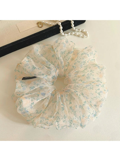 Close-up of green tulle fabric with small delicate flowers on scrunchie