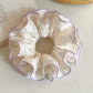 Sweet purple scrunchie with white polka dots on a white background