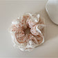 Gifty scrunchie worn on a wrist, displaying floral print and lace detail