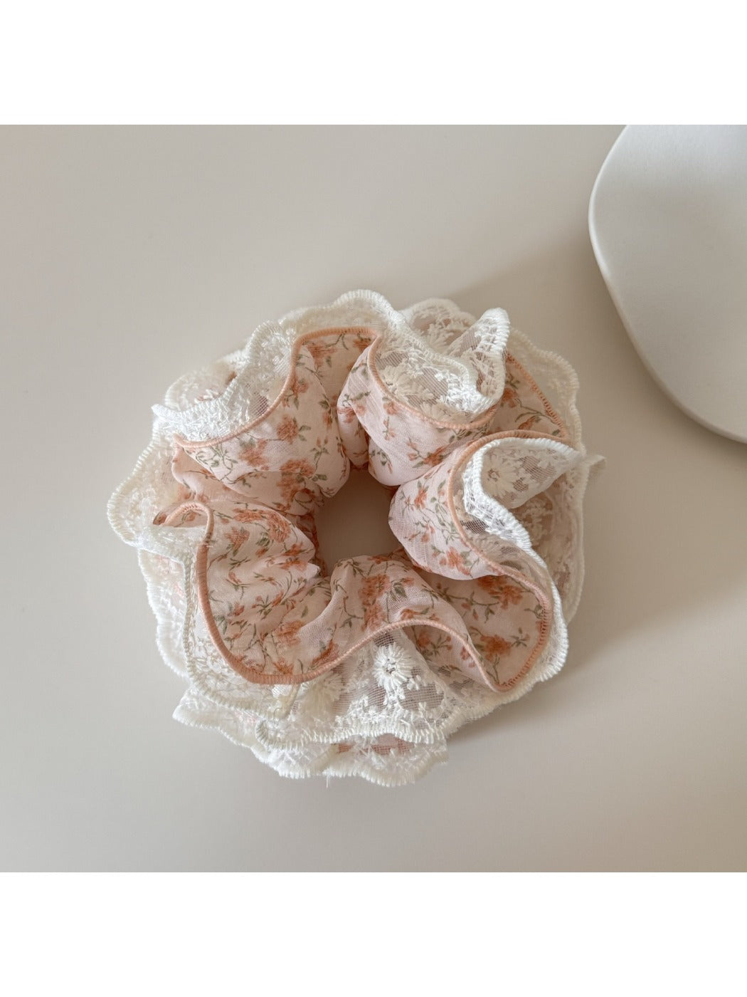 Gifty scrunchie worn on a wrist, displaying floral print and lace detail