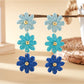 Flower shaped drop earrings with bright multicolor petals on a black surface