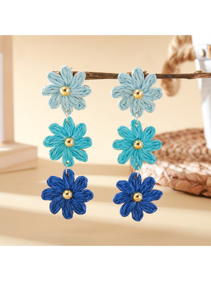Flower shaped drop earrings with bright multicolor petals on a black surface