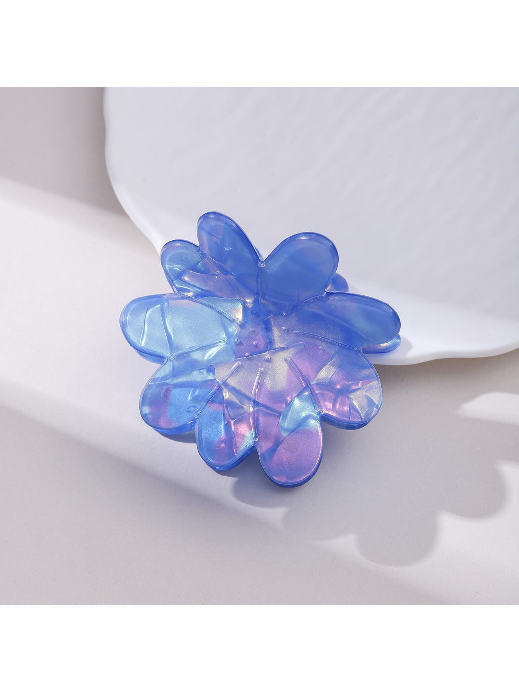 Blue flower hair clip displayed on a flat surface with soft lighting