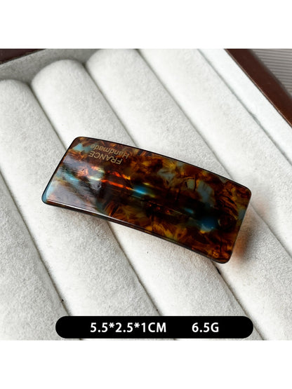 Beau curved bar hair clip clipped into dark hair with soft waves