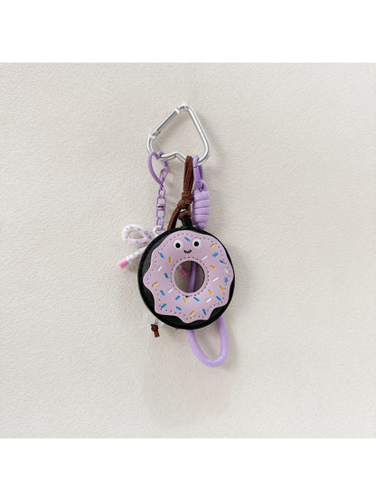 Hand holding the pink donut keychain with a blurred background