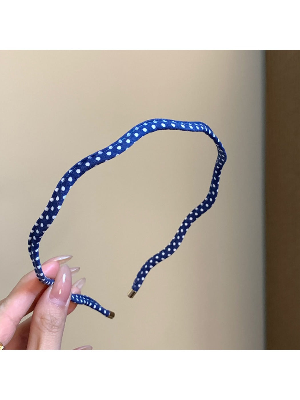 Thin wavy headband worn on model's head with black and white polka dot design