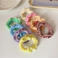 Hand holding multiple ruffled hair ties in pastel and bright colors