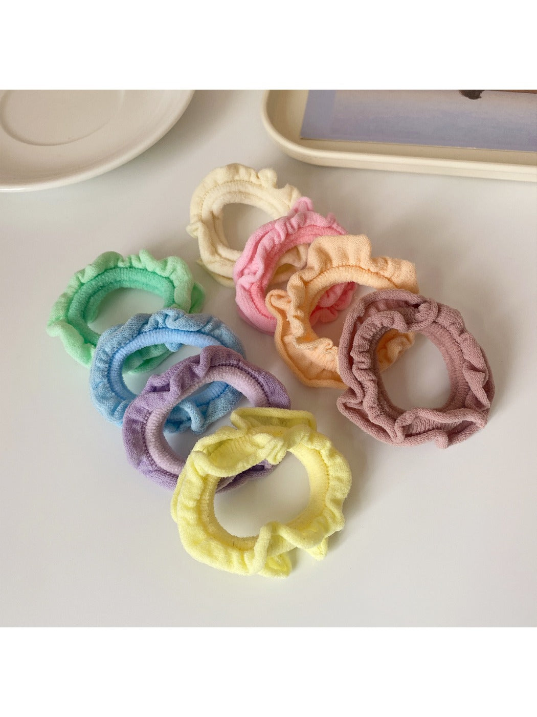 Hand holding multiple ruffled hair ties in pastel and bright colors