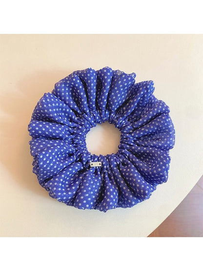 Chic blue scrunchie with white polka dots on a white background