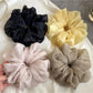 Solid color ruched scrunchie stretched slightly to show elasticity