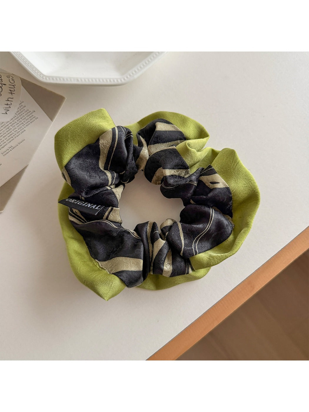 Gifty scrunchie wrapped around a ponytail on a model with dark hair