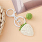 Hand holding the strawberry charm keychain with a blurred background