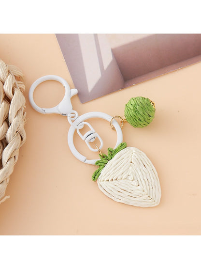 Hand holding the strawberry charm keychain with a blurred background