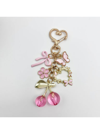 Cherry bow charm keychain displayed on a wooden surface with natural lighting