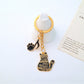 Cartoon cat piano keychain shown next to a smartphone for size comparison