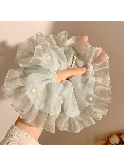 Close-up of mint green mesh fabric with white polka dots on scrunchie