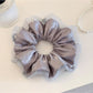 Multiple pink satin ruched scrunchies stacked together on a flat surface