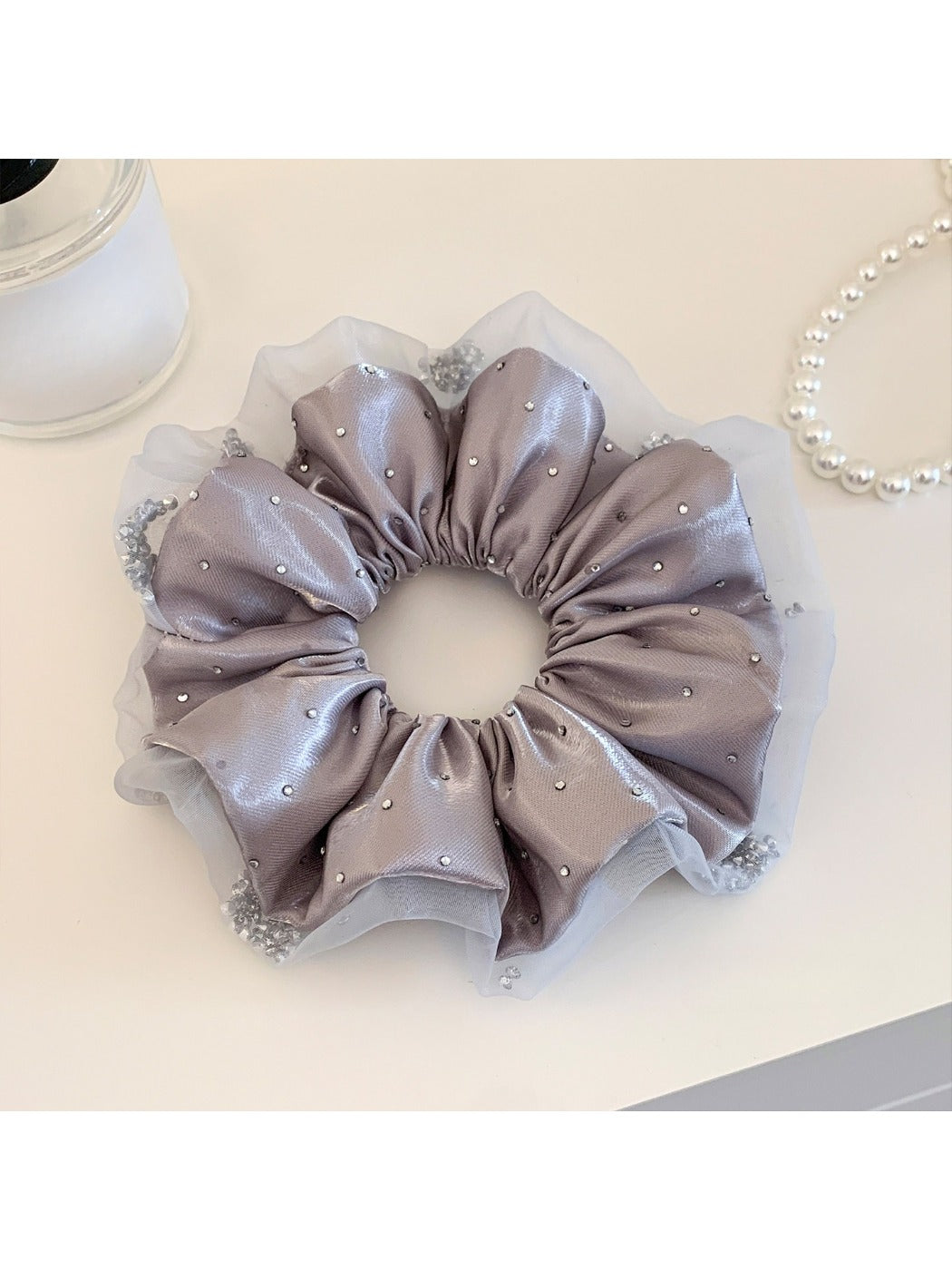 Multiple pink satin ruched scrunchies stacked together on a flat surface