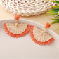 Earrings shown from above highlighting fan shape and woven raffia