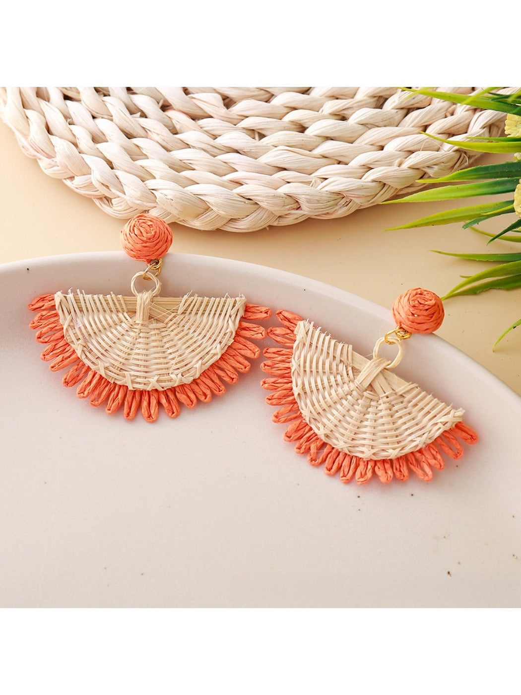 Earrings shown from above highlighting fan shape and woven raffia