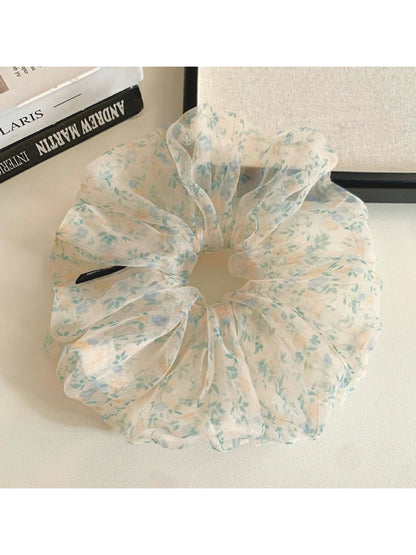 Green floral scrunchie styled on a wrist showing its volume and texture
