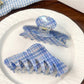 Blue plaid shark hair claw clip held in hand showing size and texture