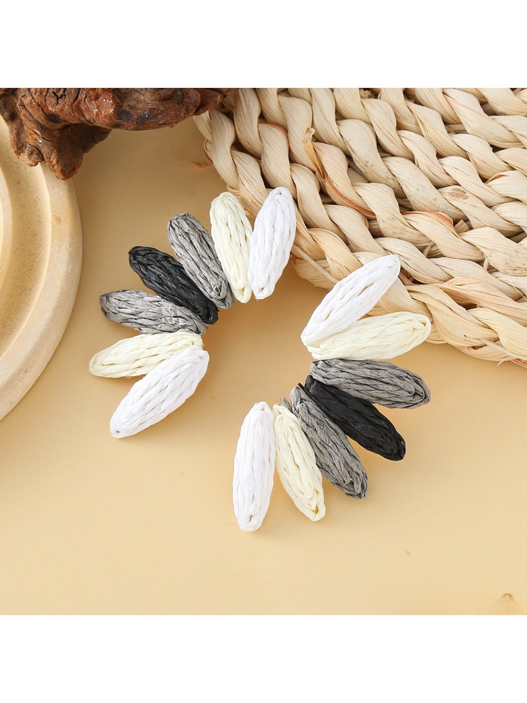 Earedge raffia earrings displayed on a wooden stand with natural lighting
