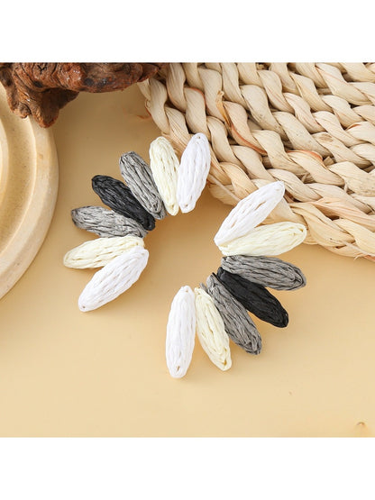 Earedge raffia earrings displayed on a wooden stand with natural lighting